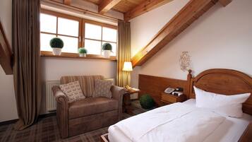 A cozy room with a bed, a sofa, a window with curtains, and a radiator.