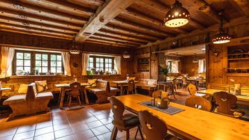 A rustic wooden interior with wooden tables and chairs, large windows, and a high ceiling with exposed beams.