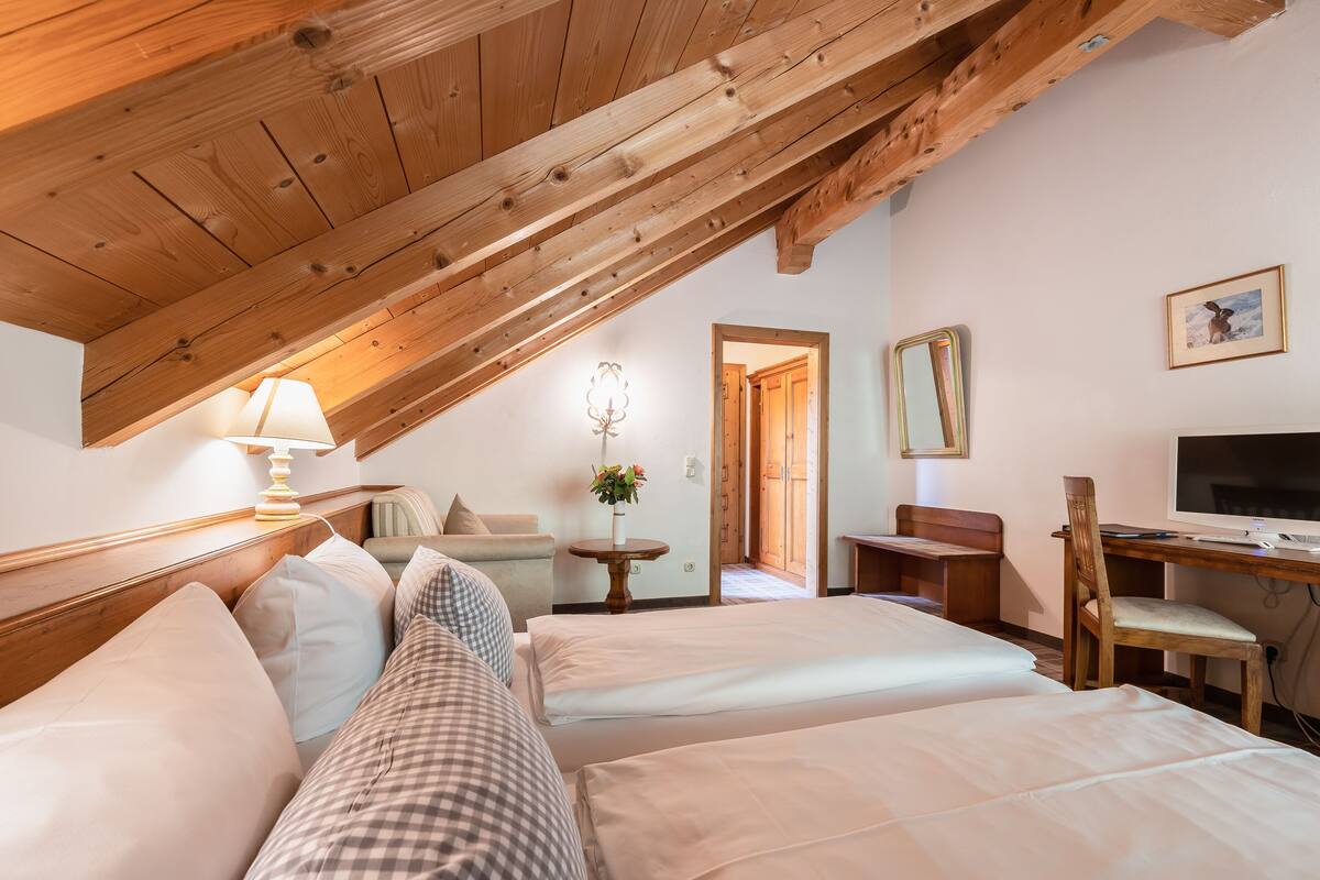 A bedroom with two beds, a desk, a chair, a TV, and a lamp.