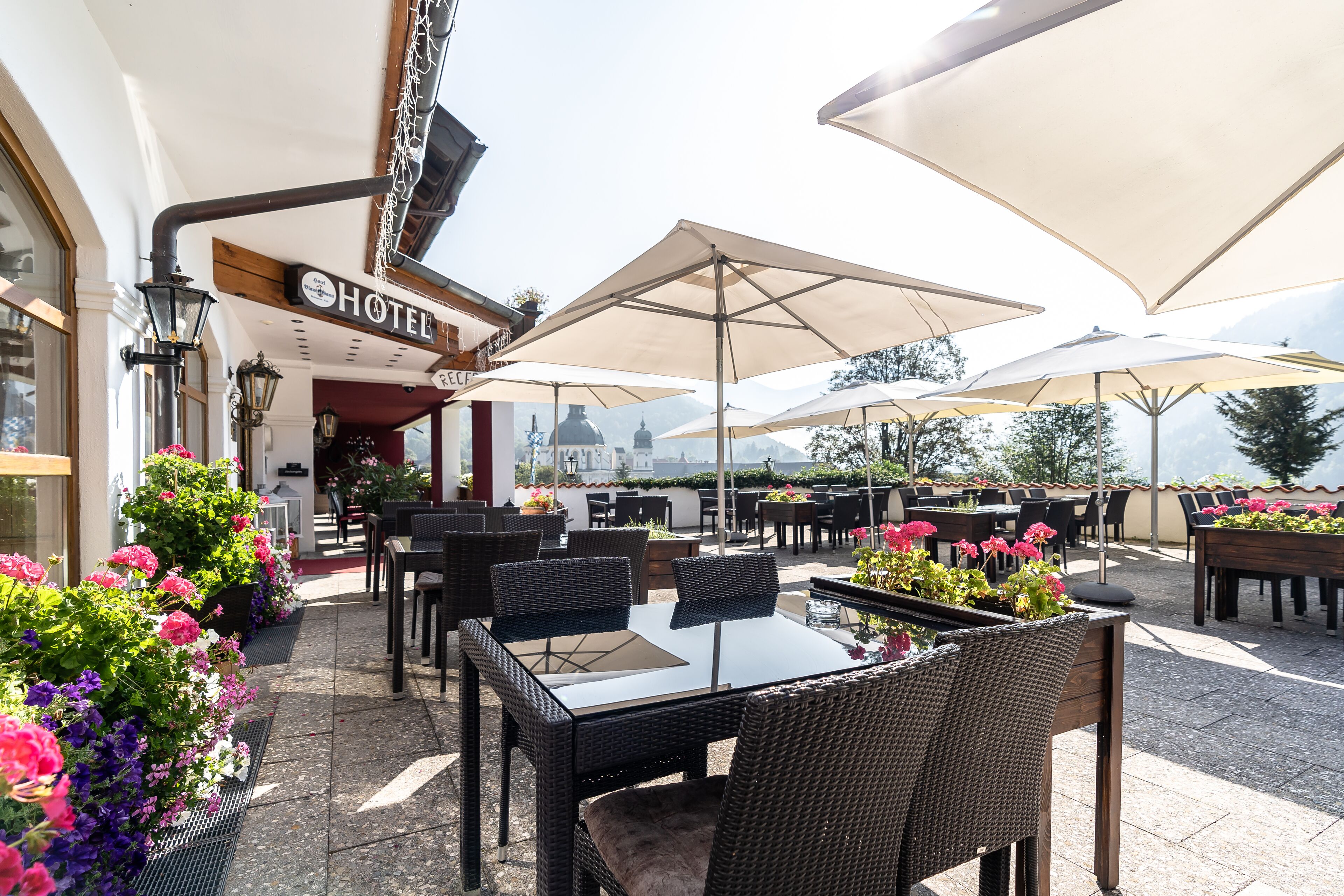 An outdoor patio with wicker furniture, large umbrellas, and potted plants.