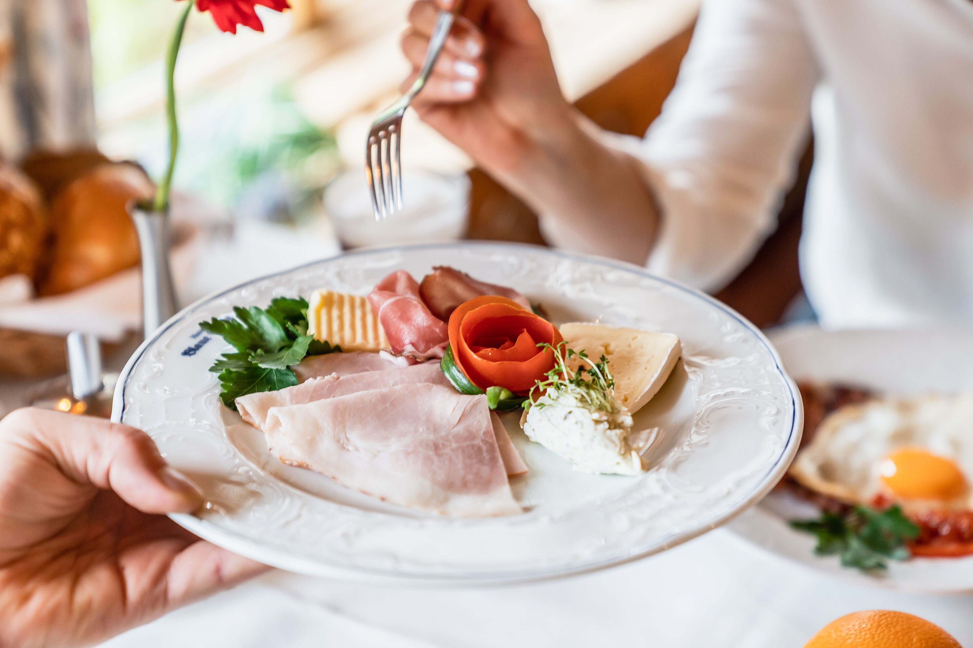 A plate with various foods including meats, vegetables, and a flower.