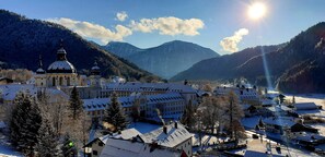A snow-covered town with a prominent church and mountains in the background. - Hotel Blaue Gams (Ettal)
