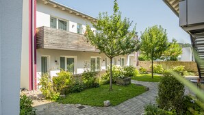 Een modern gebouw met twee verdiepingen, een balkon, een verzorgde tuin en een geplaveid pad.