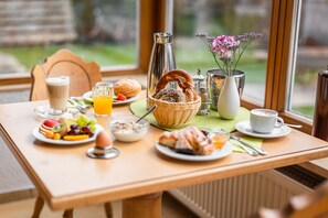 Une table de petit-déjeuner avec divers aliments, une tasse de café et un vase rempli de fleurs.
