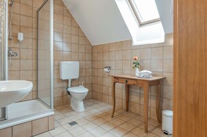 Un baño pequeño y moderno con tragaluz, inodoro, lavabo y tocador de madera.
