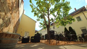 An outdoor seating area with chairs and tables, a large planter, and a tree. - Altstadthotel Fürth (Fuerth)