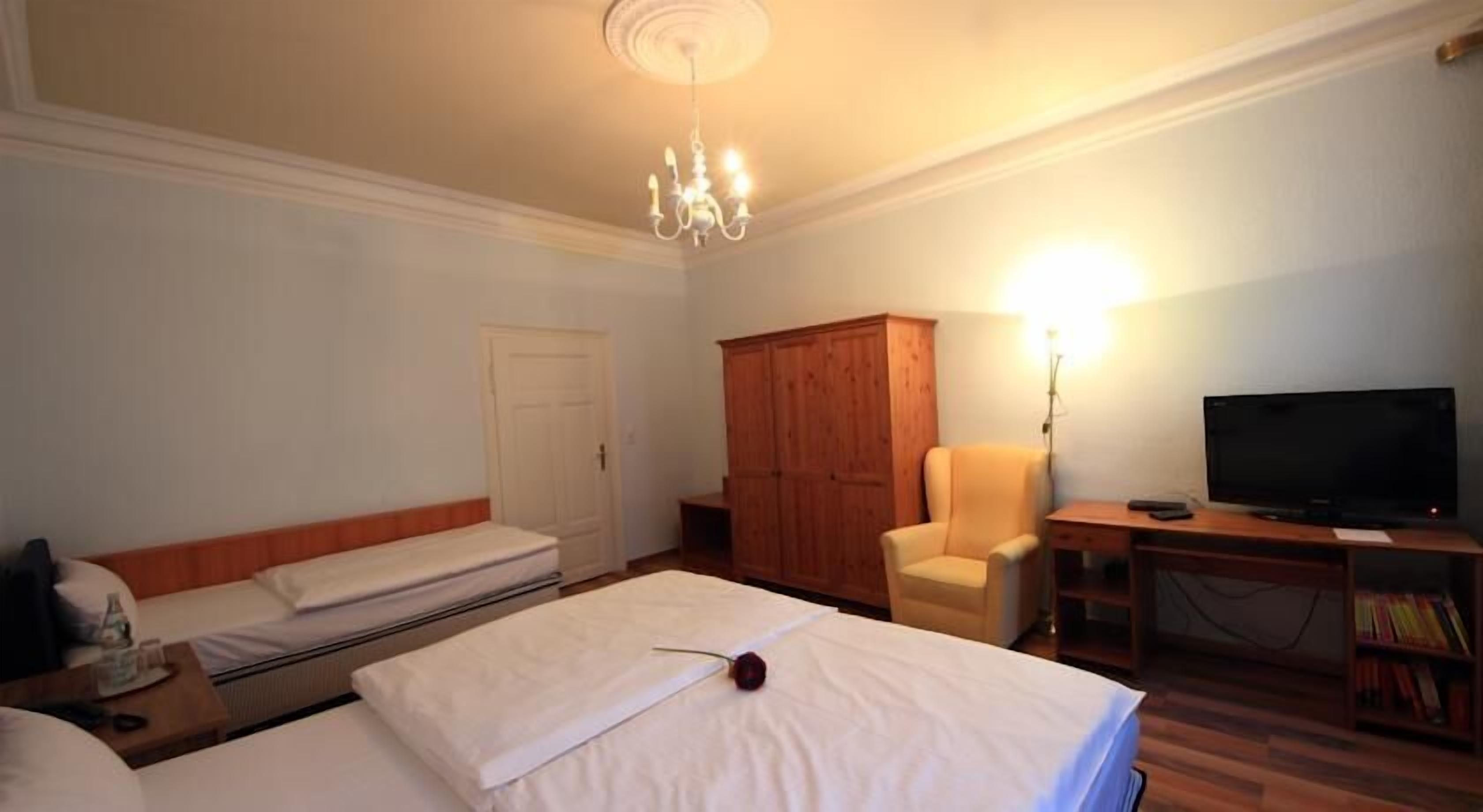 Habitación de hotel con dos camas, un armario de madera, un escritorio con televisor y una silla.