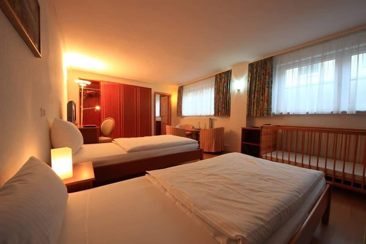 A hotel room with two beds, a desk, a chair, and a window with curtains.