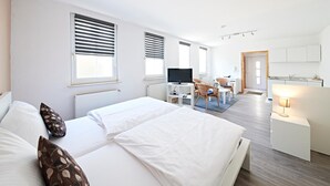 A hotel room with a large bed, a TV, a desk, and a kitchenette. - Altstadthotel Fürth (Fuerth)