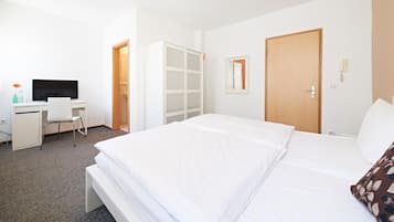 Ein Hotelzimmer mit Bett, Schreibtisch mit Stuhl, Fernseher, Kleiderschrank und einer Tür.