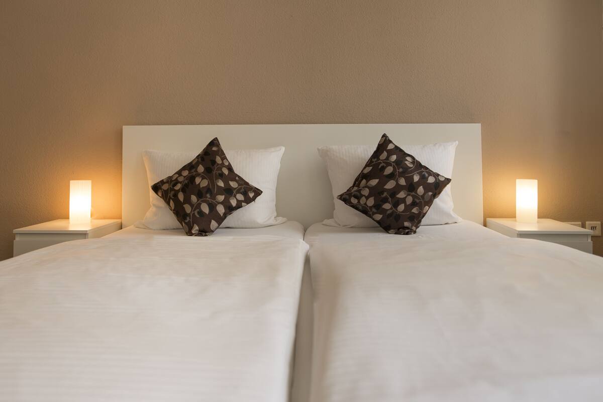 A double bed with white bedding and two patterned pillows.