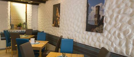 A restaurant with booths and tables, white textured walls, and two paintings.