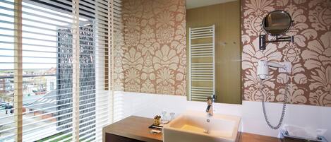A bathroom with a large window, a sink, a mirror, and a towel rack.