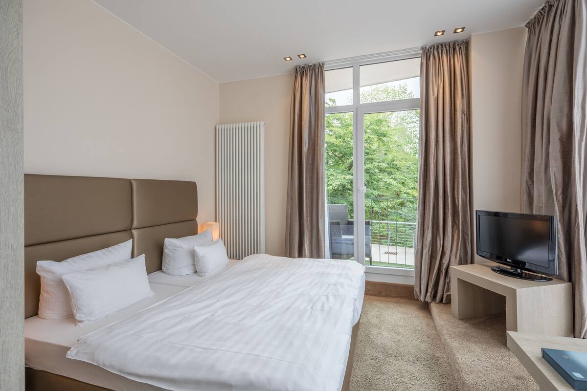 Ein modernes Hotelzimmer mit einem großen Bett, einem Flachbildfernseher und Blick ins Freie.