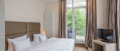 Una habitación de hotel moderna con una cama grande, un televisor de pantalla plana y vistas al exterior.