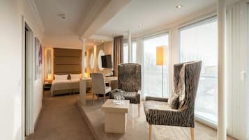 Une chambre d’hôtel équipée d’un lit, d’un bureau, d’une chaise, d’un canapé et d’une grande fenêtre avec des stores.