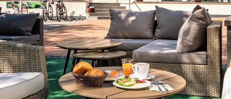 Una terraza en la azotea con mobiliario exterior, una mesa de comedor y una bicicleta estacionada al fondo.