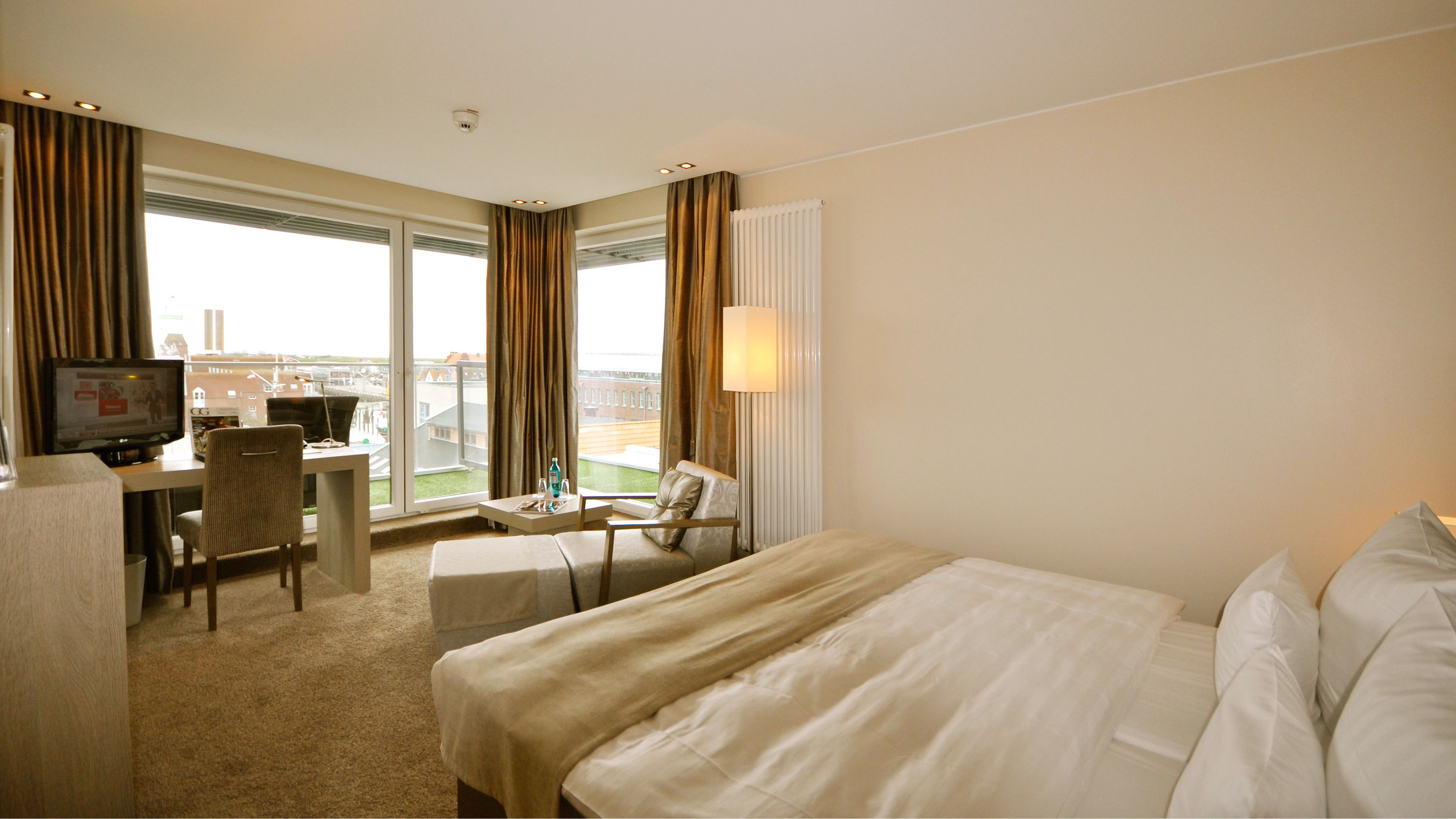 Habitación de hotel con dos camas, un escritorio, una silla, un televisor y una ventana con cortinas.