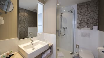 Une salle de bain moderne avec un grand miroir, un lavabo, une douche et des toilettes.