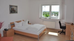 Une chambre d’hôtel moderne équipée d’un lit, d’une table de chevet, d’une lampe et d’un bureau avec une chaise.