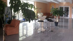 Un hall d’entrée spacieux avec un comptoir de réception, un espace salon et des plantes en pot.