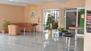 Un hall d’entrée avec un canapé, deux tabourets de bar, une plante en pot et une affiche accrochée au mur.