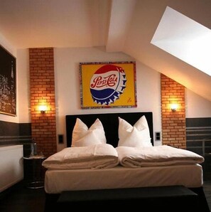 Una habitación de hotel con una cama, un muro decorativo de ladrillo y un letrero de Pepsi Cola sobre la cama.
