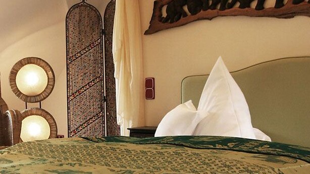 A bed with a canopy, a wall-mounted mirror, and a decorative wall piece. - HIP Hotel (Heidelberg)