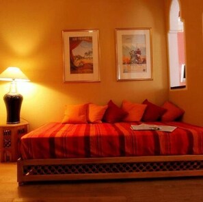 Una habitación de hotel con una cama, una lámpara y dos cuadros en la pared.