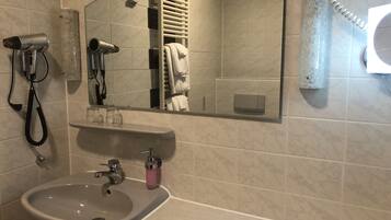 A bathroom with a sink, a mirror, a towel rack, and a hairdryer.