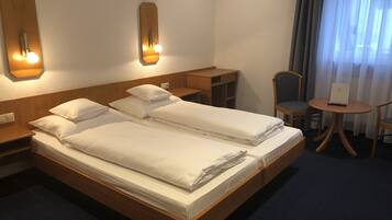 A hotel room with a double bed, a desk, a chair, and a small table.
