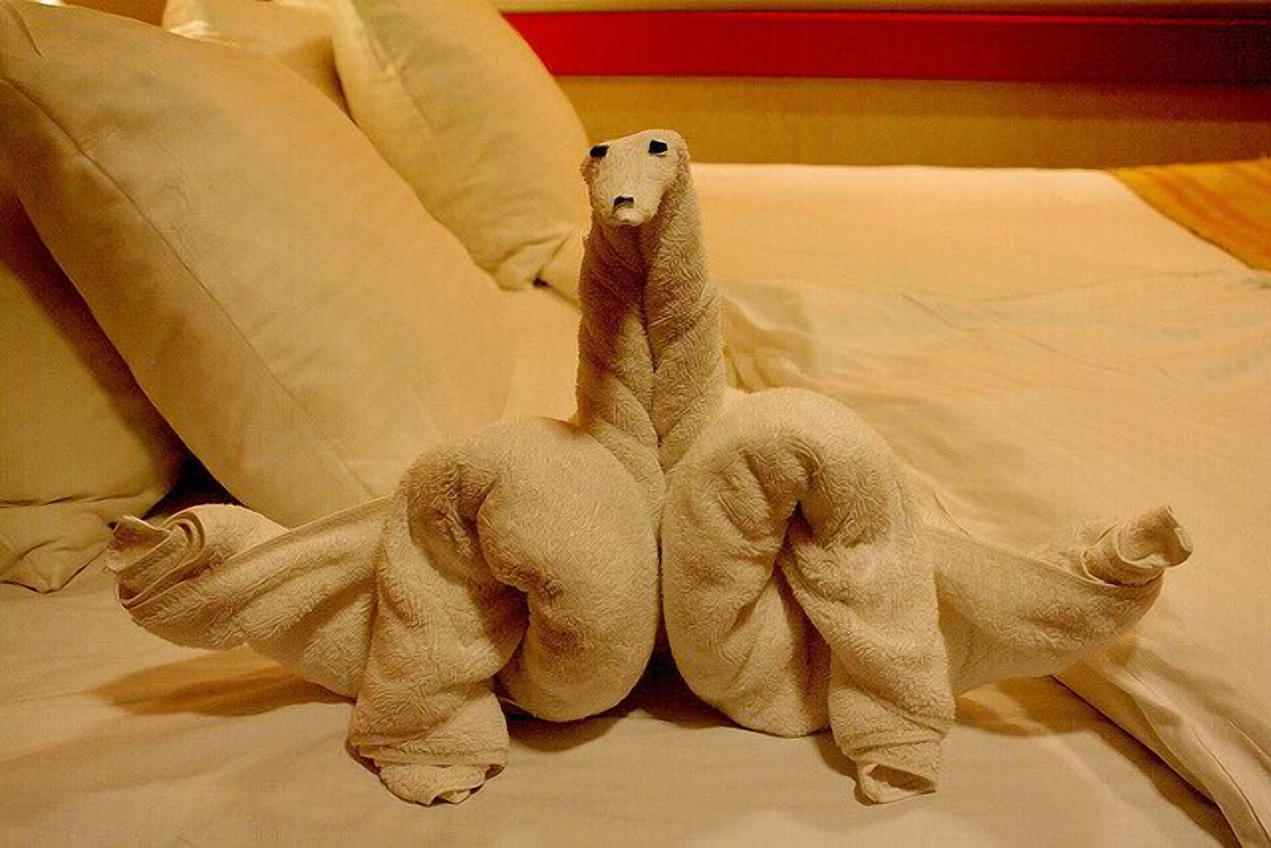 A bed with a unique dinosaur-shaped towel.
