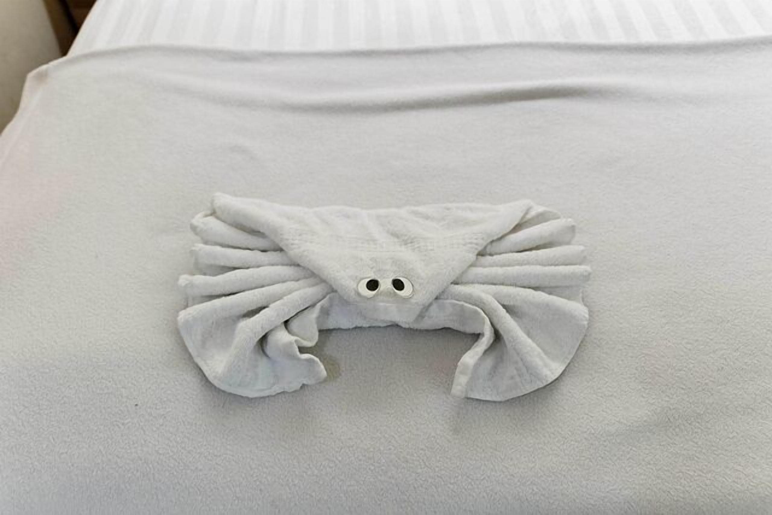 A neatly folded towel on a bed with a striped pillow.