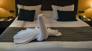 Een bed met een handdoek in de vorm van een zwaan en twee zwarte kussens.