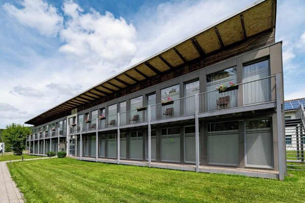 Un edificio moderno con varios balcones, ventanas amplias y un paseo techado.