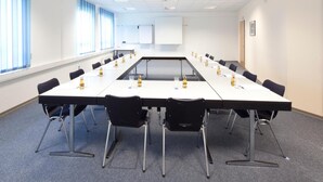 A conference room with a long table, black chairs, and water bottles on the table. - Hotel Vicinity (Hoppstaedten-Weiersbach)