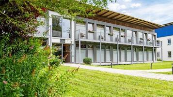Een modern gebouw met meerdere balkons, grote ramen en een verzorgd gazon.