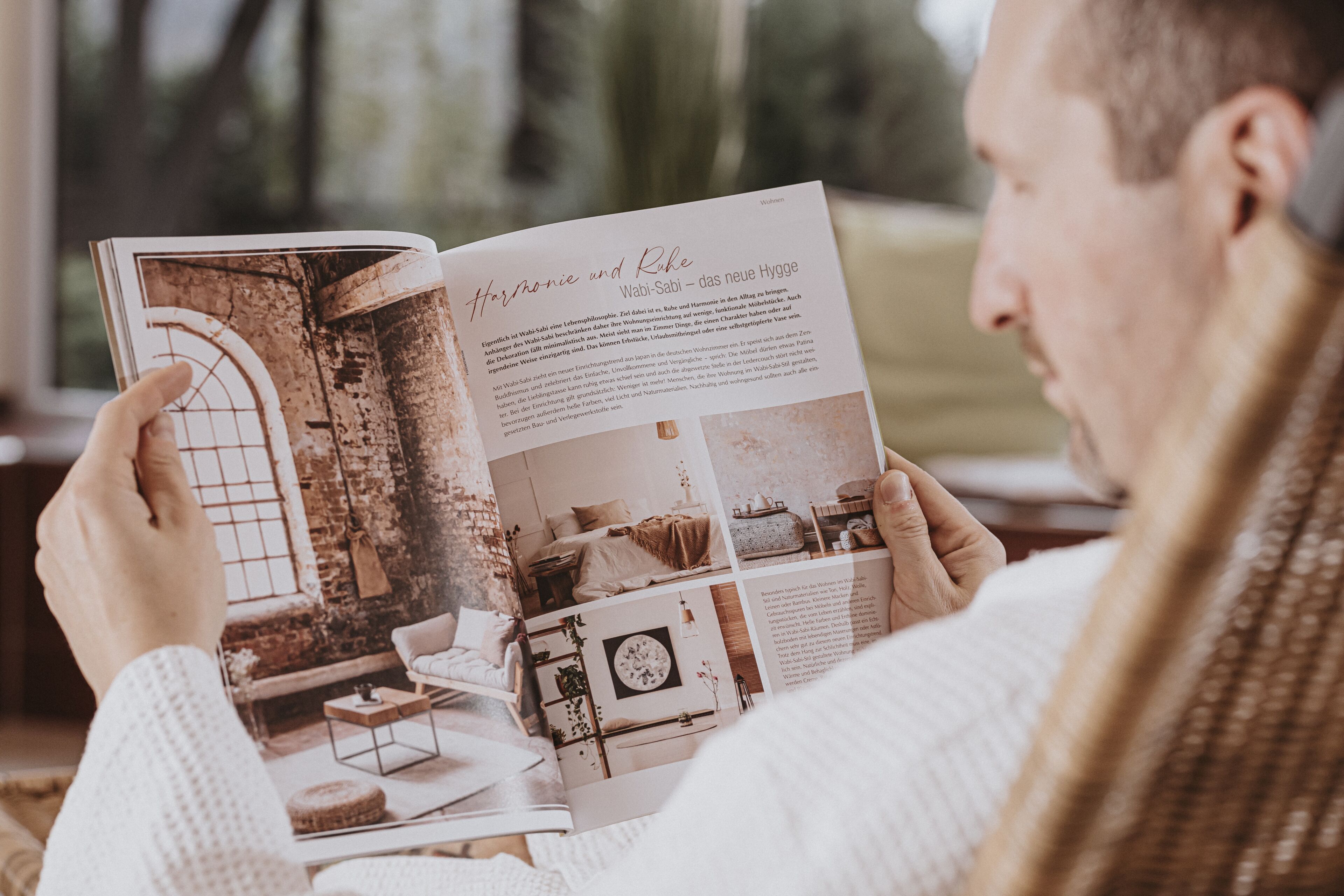Una persona leyendo una revista con imágenes de diseño de interiores.
