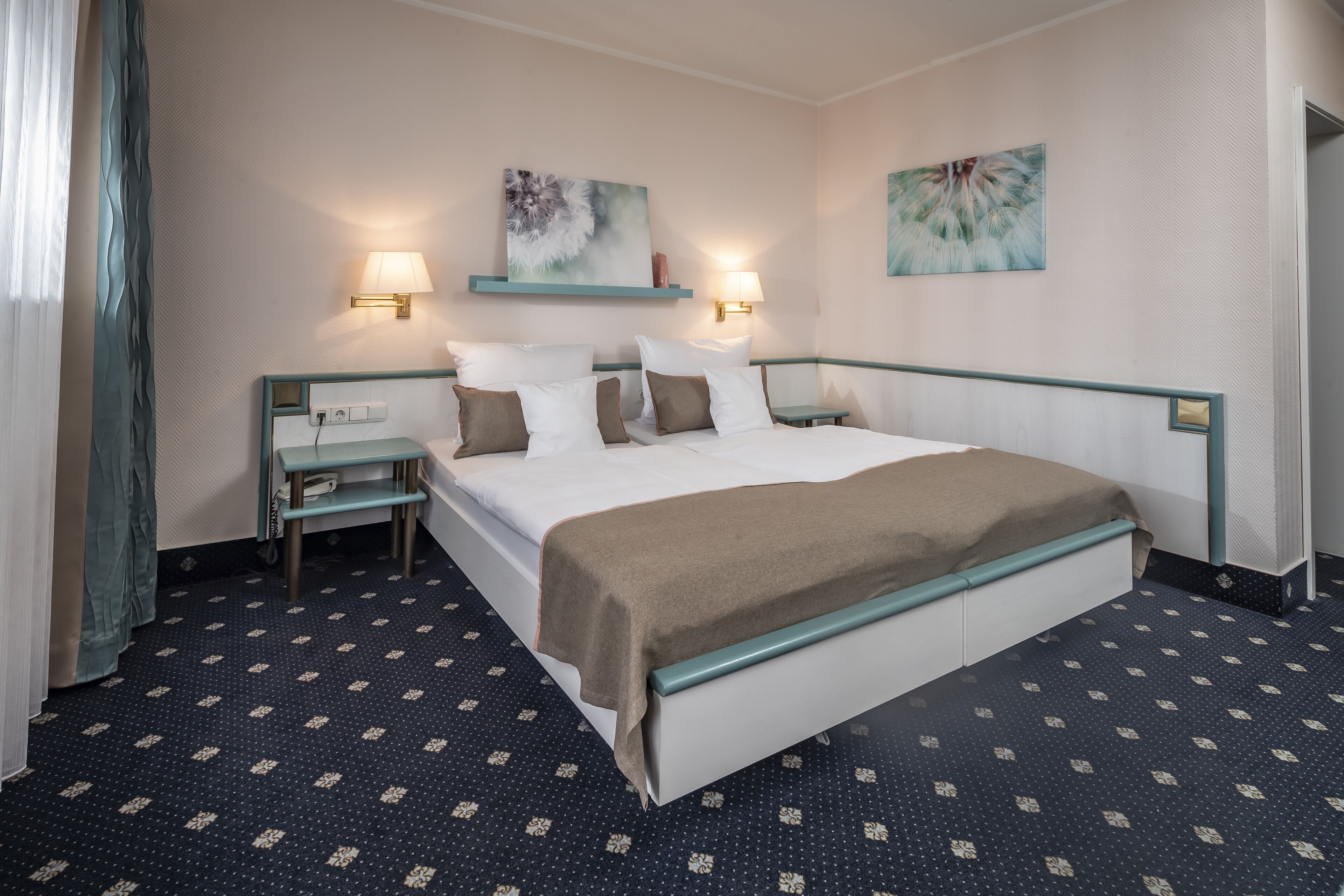 A hotel room with a large bed, two bedside tables, a nightstand, and a wall-mounted lamp.