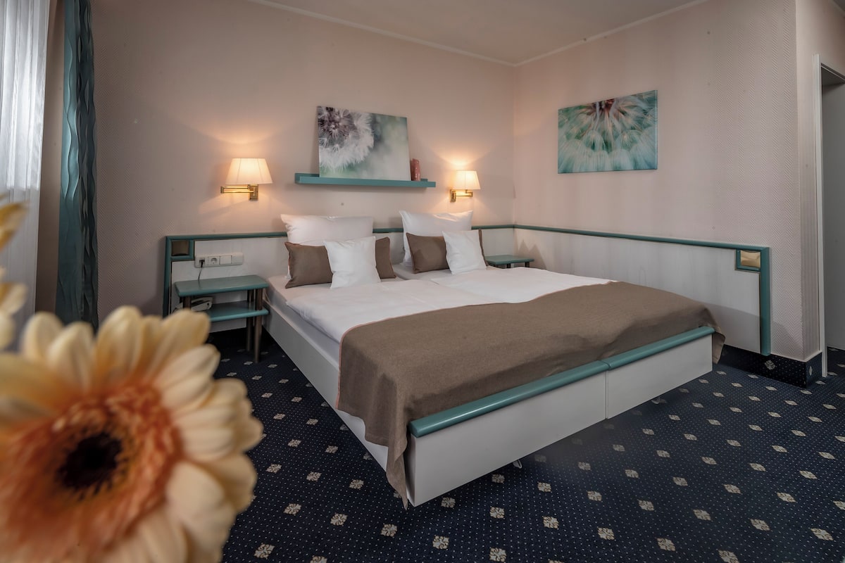 Una habitación de hotel con una cama grande, dos mesitas de noche y una lámpara de pared.