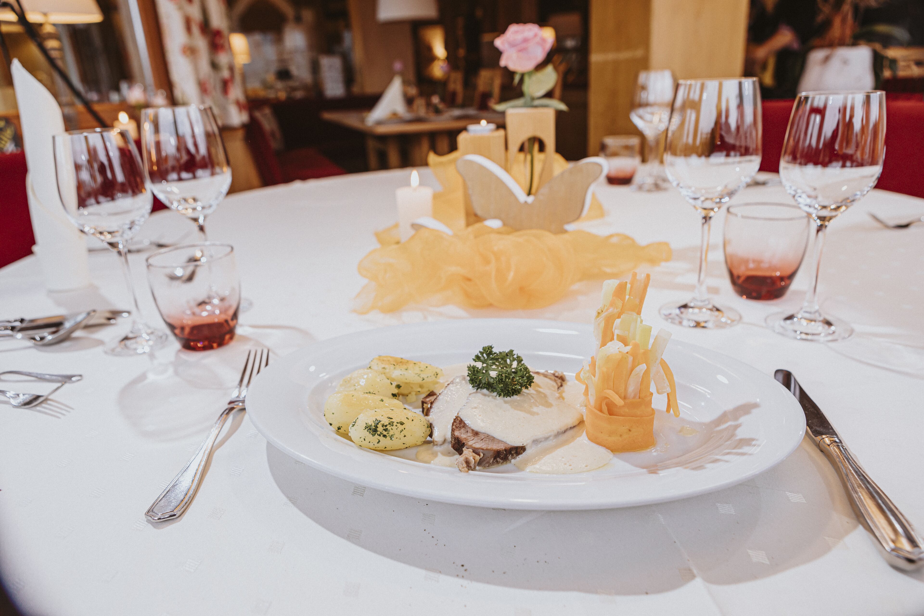 Una mesa de comedor con mantel blanco, un plato de comida y varias copas de vino.