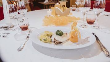 Una mesa de comedor con mantel blanco, un plato de comida y varias copas de vino.