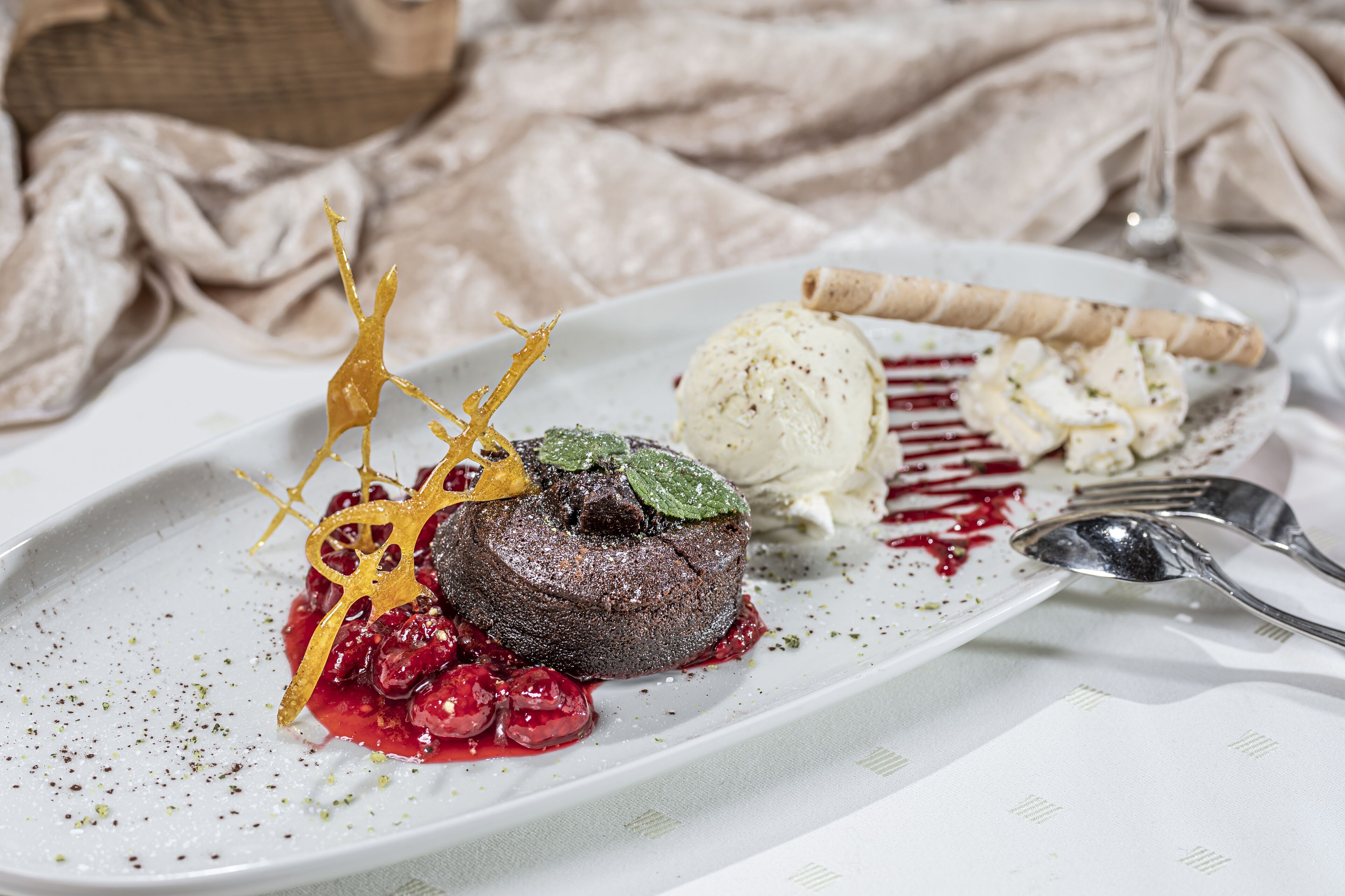 A dessert plate with a chocolate lava cake, ice cream, and a berry sauce.
