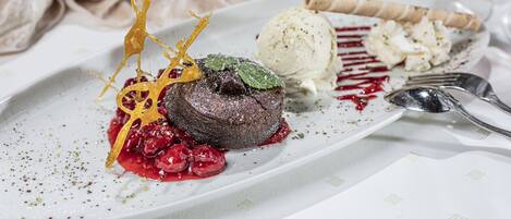 A dessert plate with a chocolate lava cake, ice cream, and a berry sauce.