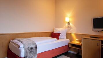 Une chambre d’hôtel avec un lit, une table de chevet, un téléviseur et une armoire en bois.