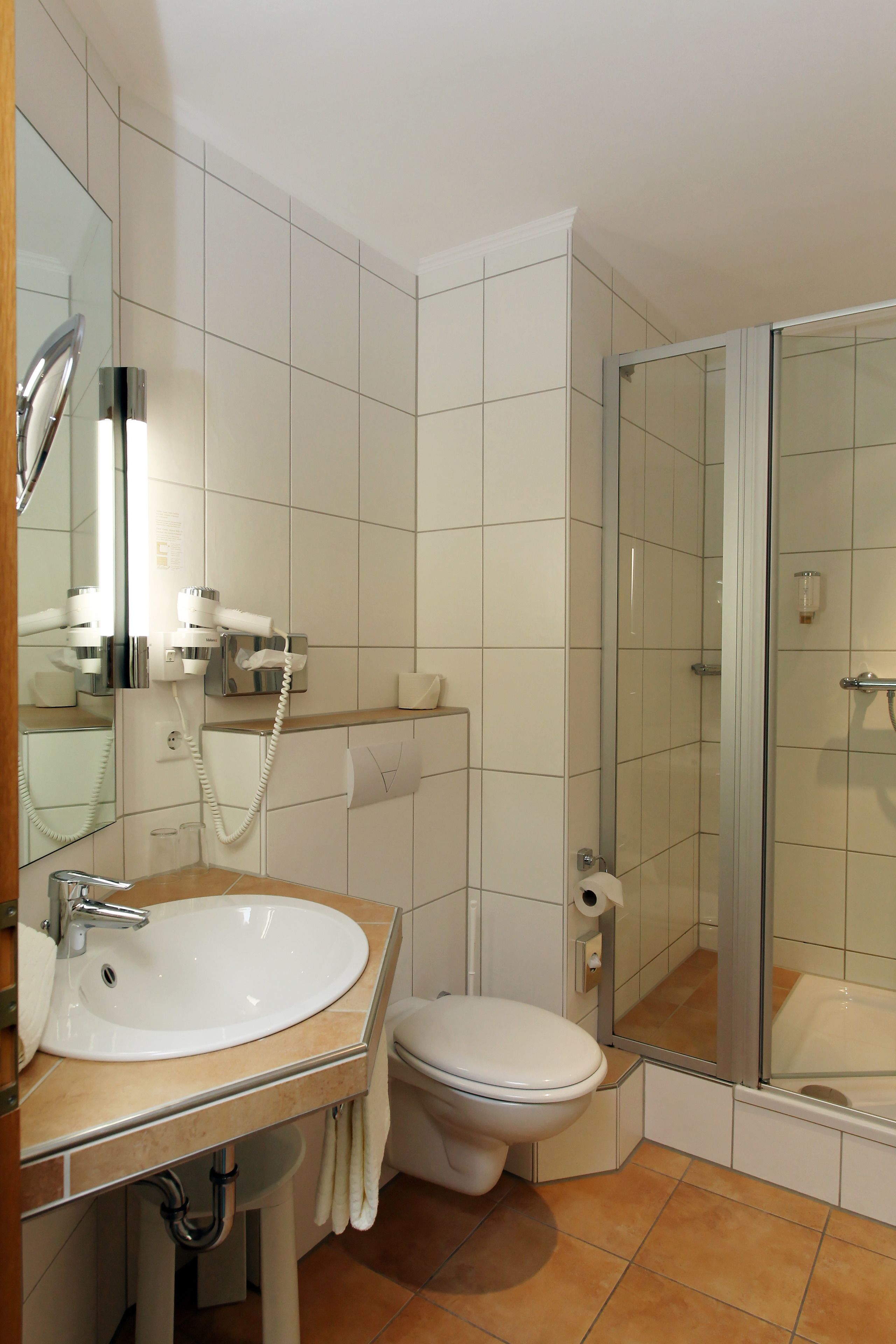 Un baño moderno con lavamanos, inodoro y cabina de ducha de vidrio.