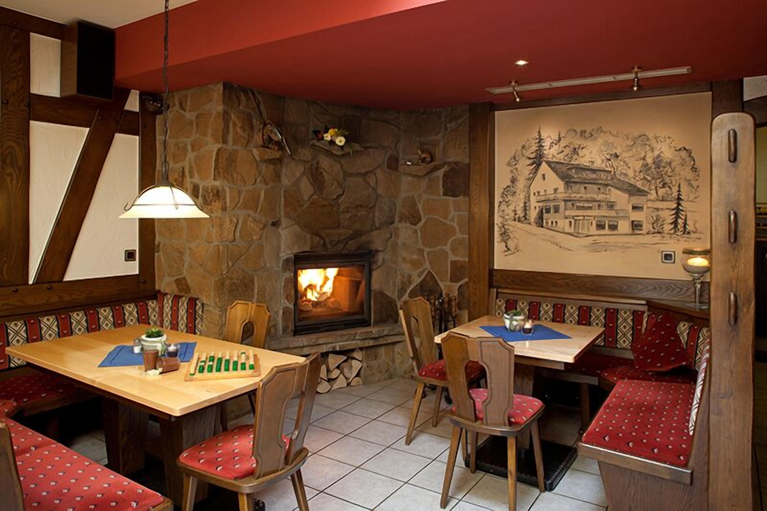 A cozy dining area with stone walls, a fireplace, and wooden furniture.