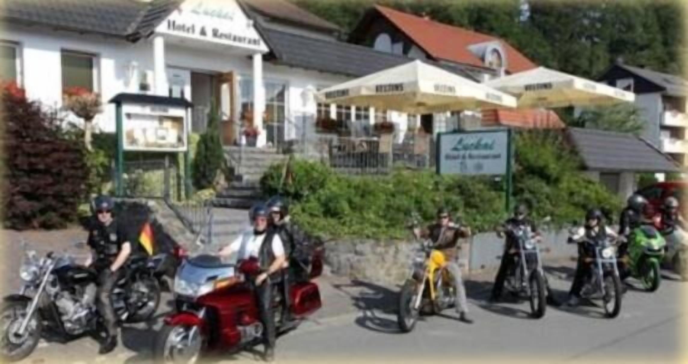 Un hotel con terraza al aire libre y motocicletas estacionadas frente a él.