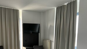 Una habitación de hotel con dos camas, un televisor de pantalla plana, un escritorio y un radiador.