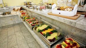 Un bufé con diversas opciones de comida, incluyendo carnes, quesos y frutas.